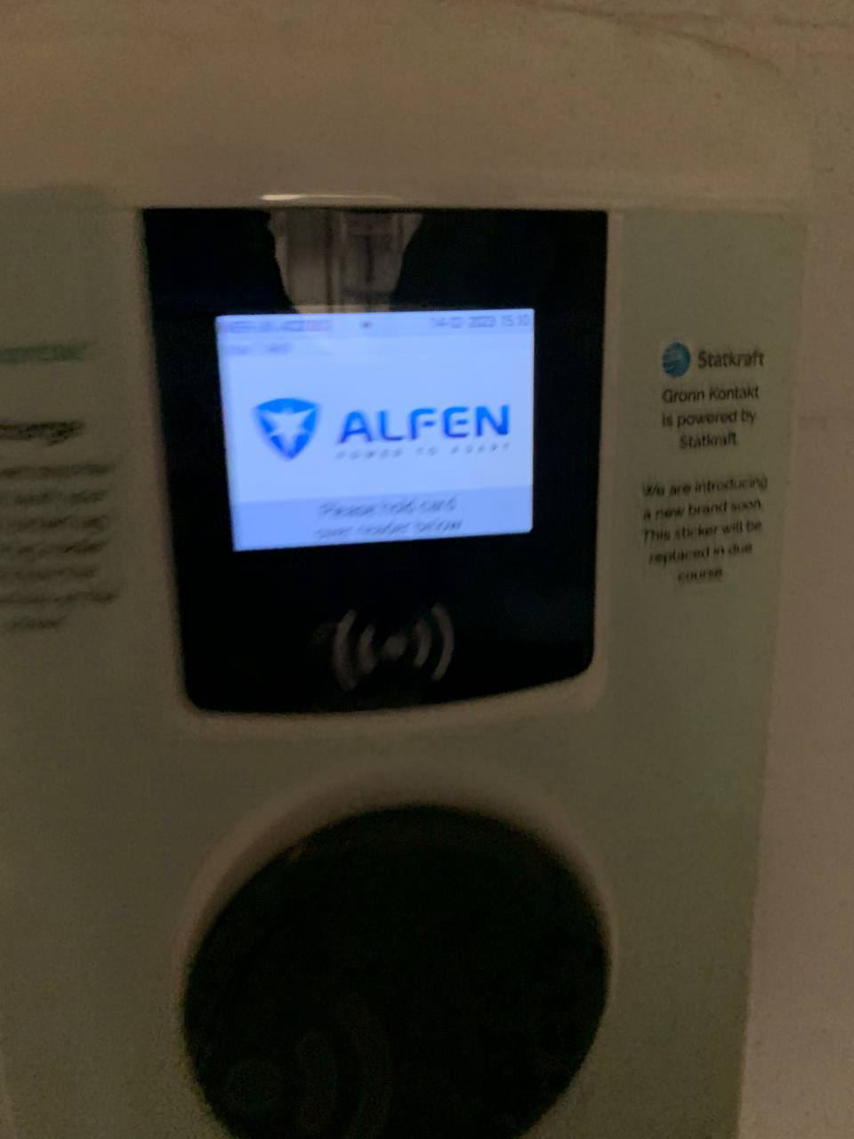 Charge point screen reading Please hold card over reader below, beside an operator sticker announcing a coming rebrand