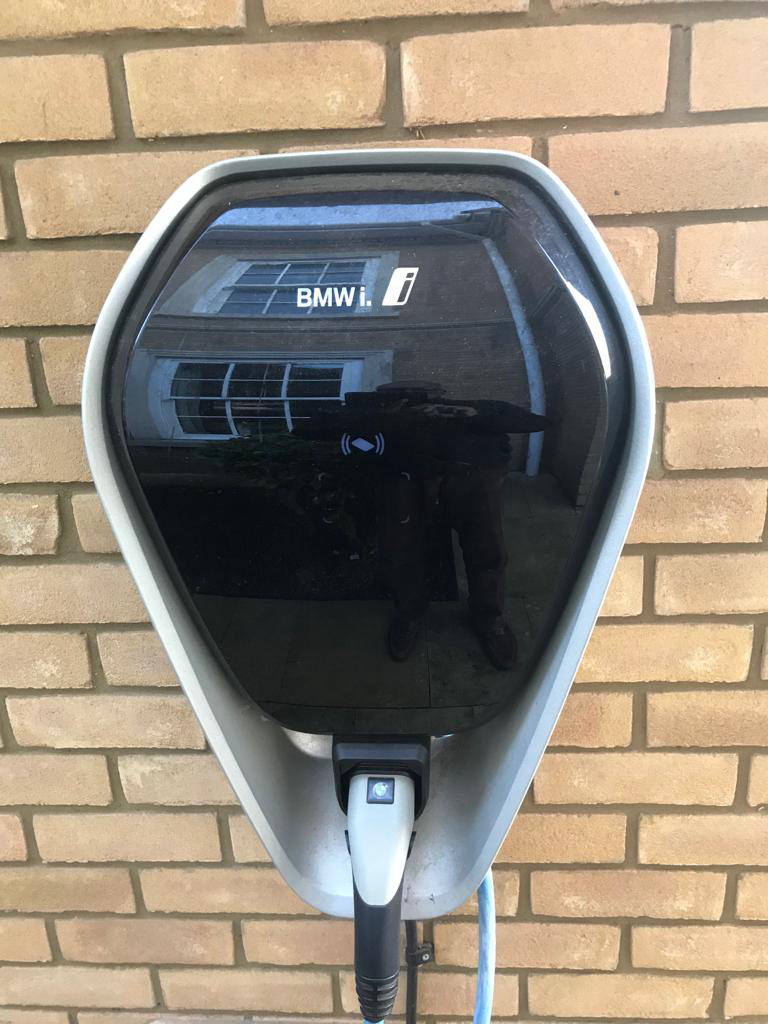 BMW i Wallbox home EV charge point mounted on a brick wall with a tethered cable