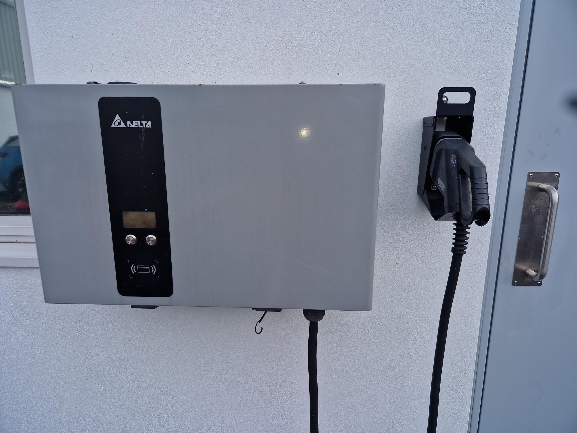 Delta EVDE25E4DUM 25 kW DC charge point on a wall with its tethered cable on a separate holster
