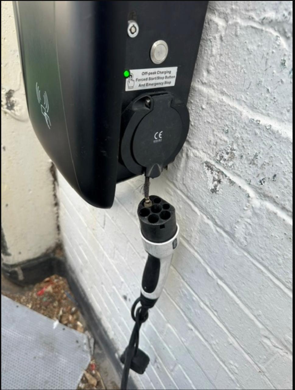 Home EV charger unit with the socket cover open and a damaged Type 2 connector hanging from a burnt cable