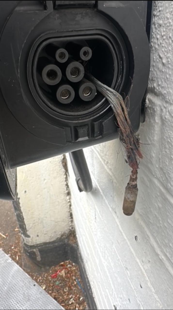 Burnt and melted Type 2 socket on a home EV charger with the charred cable conductors hanging out