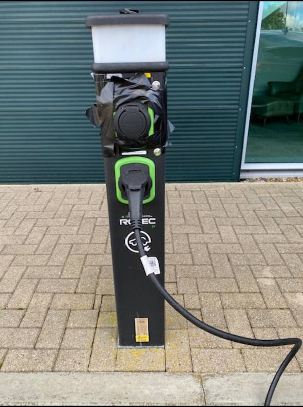 Rolec EV charge point with its upper socket wrapped in black plastic sheeting and tape as a homemade rain cover